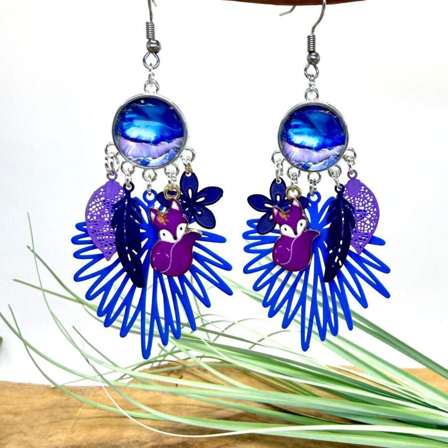 Boucles d'oreilles fantaisie bleu et violet avec cabochon rond, petit renard mauve émaillé, fleur bleue, feuilles décoratives et estampe ajourée bleue.