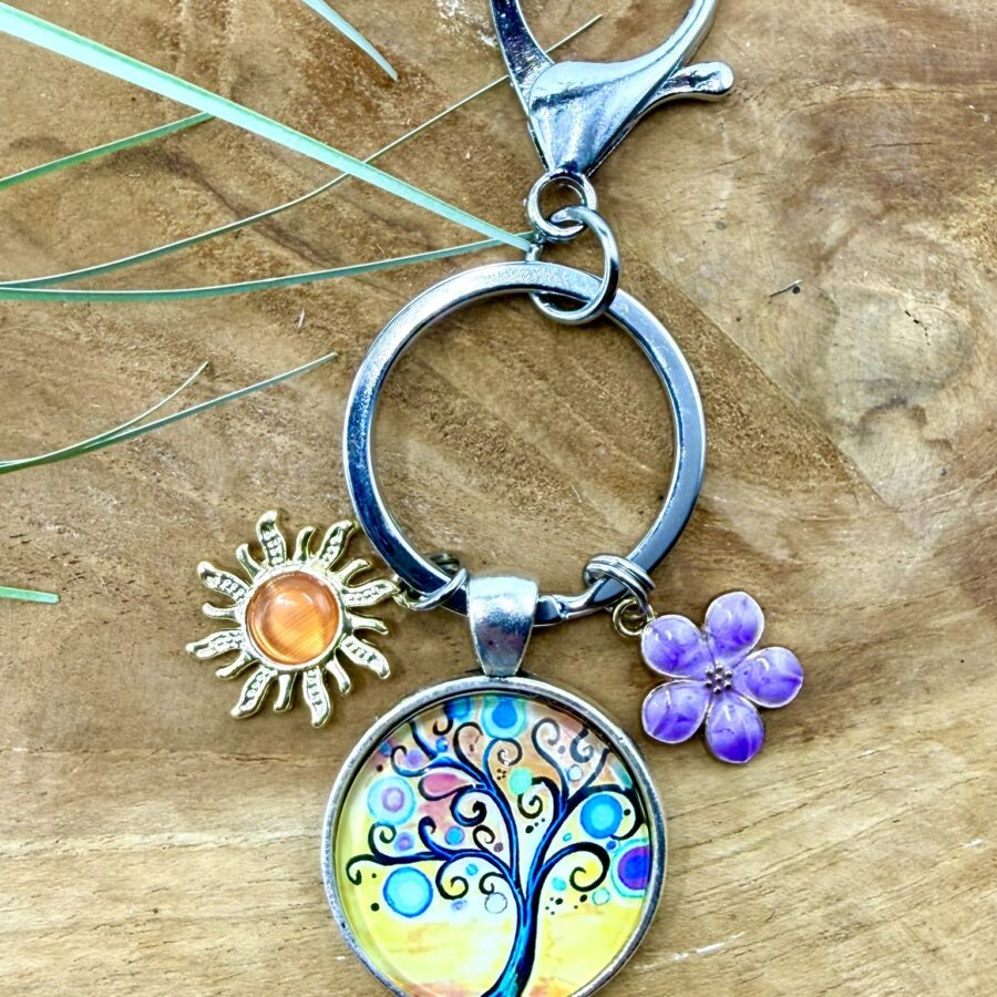 Porte-clés arbre de vie en acier inoxydable avec cabochon de 25 mm représentant un arbre de vie coloré, breloque soleil doré et fleur violette.